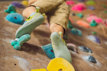 little boy climbing a rock wall in special boots. indoorの写真素材