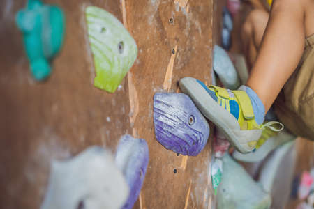 little boy climbing a rock wall in special boots. indoorの写真素材
