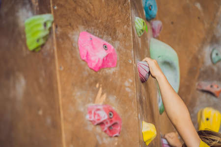 little boy climbing a rock wall in special boots. indoorの写真素材