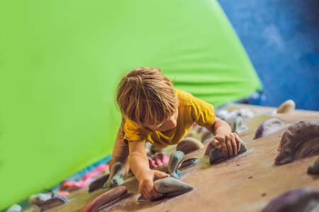 little boy climbing a rock wall in special boots. indoorの写真素材