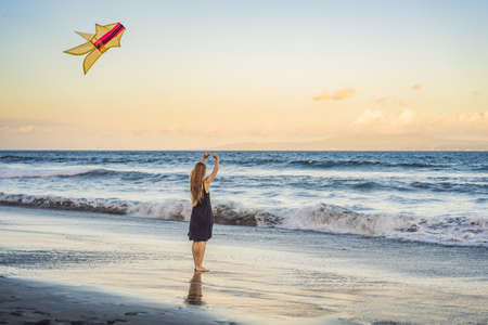 A young woman launches a kite on the beach. Dream, aspirations, future plansの写真素材
