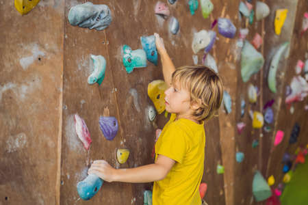 little boy climbing a rock wall in special boots. indoorの写真素材