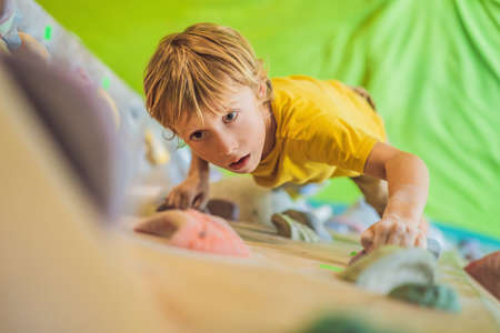 little boy climbing a rock wall in special boots. indoorの写真素材