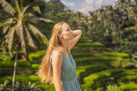Beautiful young woman walk at typical Asian hillside with rice farming, mountain shape green cascade rice field terraces paddies. Ubud, Bali, Indonesia. Bali travel conceptの写真素材