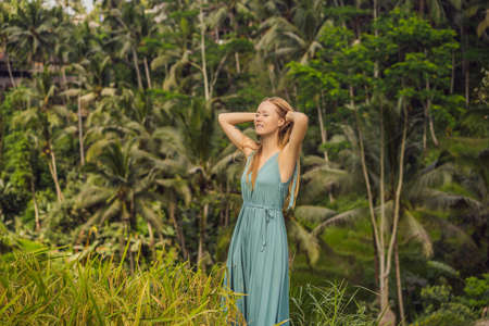 Beautiful young woman walk at typical Asian hillside with rice farming, mountain shape green cascade rice field terraces paddies. Ubud, Bali, Indonesia. Bali travel conceptの写真素材