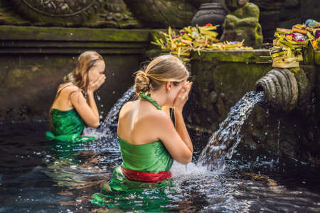 Two women in holy spring water temple in bali. The temple compound consists of a petirtaan or bathing structure, famous for its holy spring waterの写真素材
