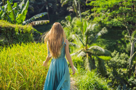 Beautiful young woman walk at typical Asian hillside with rice farming, mountain shape green cascade rice field terraces paddies. Ubud, Bali, Indonesia. Bali travel conceptの写真素材
