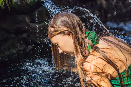 Woman in holy spring water temple in bali. The temple compound consists of a petirtaan or bathing structure, famous for its holy spring waterの写真素材