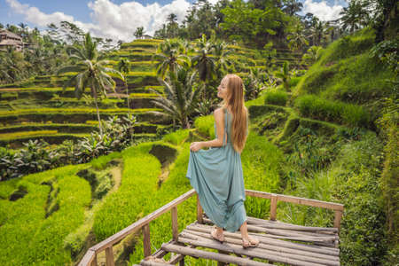 Beautiful young woman walk at typical Asian hillside with rice farming, mountain shape green cascade rice field terraces paddies. Ubud, Bali, Indonesia. Bali travel conceptの写真素材