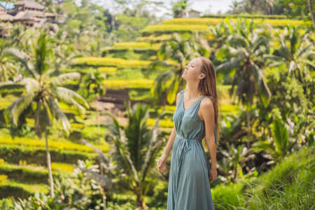 Beautiful young woman walk at typical Asian hillside with rice farming, mountain shape green cascade rice field terraces paddies. Ubud, Bali, Indonesia. Bali travel conceptの写真素材