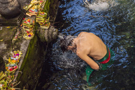 Man in holy spring water temple in bali. The temple compound consists of a petirtaan or bathing...