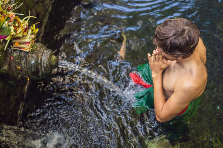Man in holy spring water temple in bali. The temple compound consists of a petirtaan or bathing structure, famous for its holy spring waterの写真素材