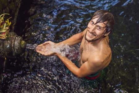 Man in holy spring water temple in bali. The temple compound consists of a petirtaan or bathing...