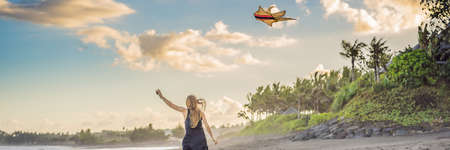 A young woman launches a kite on the beach. Dream, aspirations, future plans BANNER, LONG FORMATの写真素材