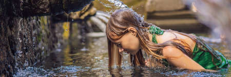 Woman in holy spring water temple in bali. The temple compound consists of a petirtaan or bathing structure, famous for its holy spring water BANNER, LONG FORMATの写真素材