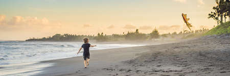 Happy young boy flying kite on the beach at sunset BANNER, LONG FORMATの写真素材
