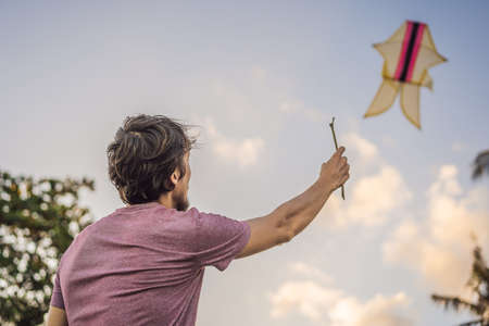 young men flying a kite at sunset on the beachの写真素材
