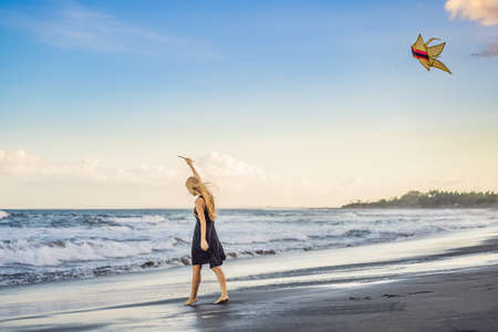 A young woman launches a kite on the beach. Dream, aspirations, future plansの写真素材