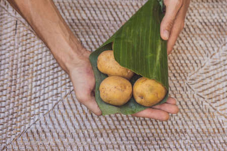 Eco-friendly product packaging concept. Potato wrapped in a banana leaf, as an alternative to a...