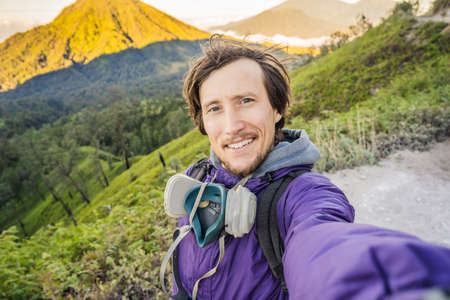 Young man tourist makes a selfie with the magnificent views on green mountains from a mountain road...