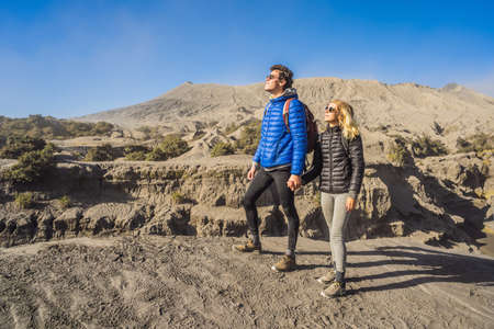 Young couple man and woman visit the Bromo volcano at the Tengger Semeru National Park on the Java Island, Indonesia. They enjoy magnificent view on the Bromo or Gunung Bromo on Indonesian, Semeru and other volcanoes located inside of the Sea of Sand within the Tengger Caldera. One of the most famous volcanic objects in the world. Travel to Indonesia conceptの写真素材