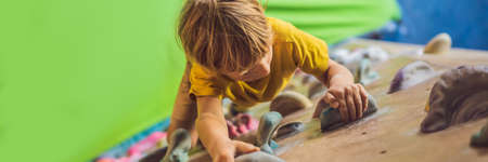 little boy climbing a rock wall in special boots. indoor BANNER, LONG FORMATの写真素材