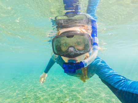 Happy woman in snorkeling mask dive underwater with tropical fishes in coral reef sea pool. Travel...
