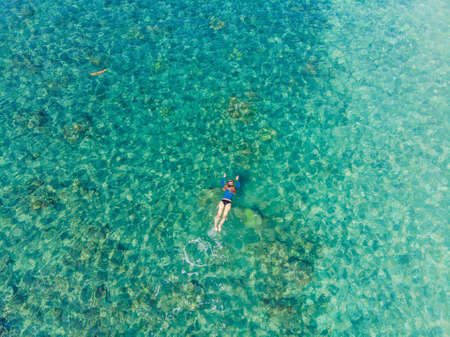 Happy woman in snorkeling mask dive underwater with tropical fishes in coral reef sea pool. Travel lifestyle, water sport outdoor adventure, swimming lessons on summer beach holiday. Aerial view from the drone.の写真素材