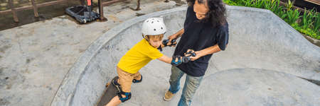 Athletic boy learns to skateboard with asian trainer in a skate park. Children education, sports. Race diversity BANNER, LONG FORMATの写真素材