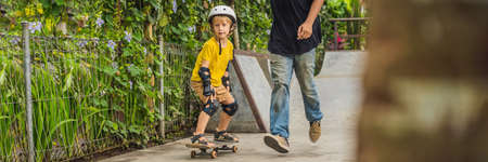 Athletic boy learns to skateboard with a trainer in a skate park. Children education, sports BANNER, LONG FORMATの写真素材