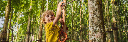 Little boy in a rope park. Active physical recreation of the child in the fresh air in the park. Training for children BANNER, LONG FORMATの写真素材