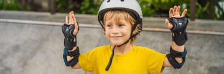 Athletic boy in helmet and knee pads learns to skateboard with in a skate park. Children education, sports BANNER, LONG FORMATの写真素材