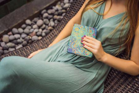 Woman reads e-book on deck chair in the garden.