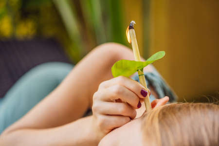 Ear candling being carried out on an attractive caucasian woman in a spaの写真素材