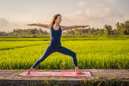 Young woman practice yoga outdoor in rice fields in the morning during wellness retreat in Baliの写真素材
