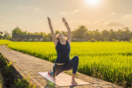 Young woman practice yoga outdoor in rice fields in the morning during wellness retreat in Baliの写真素材