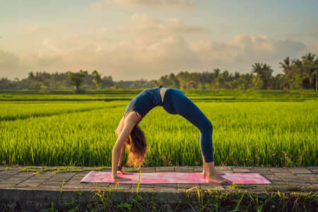 Young woman practice yoga outdoor in rice fields in the morning during wellness retreat in Baliの写真素材