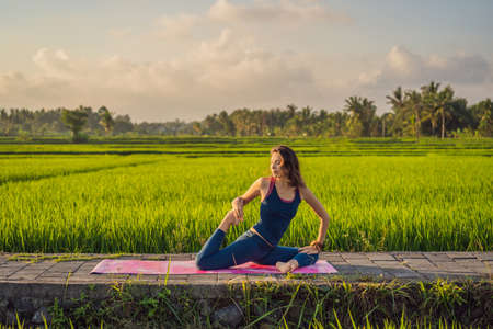 Young woman practice yoga outdoor in rice fields in the morning during wellness retreat in Baliの写真素材