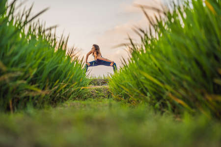 Young woman practice yoga outdoor in rice fields in the morning during wellness retreat in Baliの写真素材