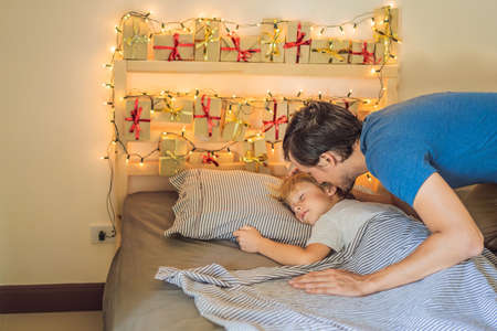 Dad wakes up little boy in the morning and home made advent calendar on a shelf. Winter seasonal tradition. Christmas advent calendarの写真素材