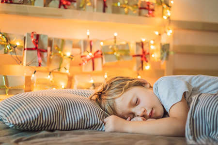 Little blond boy sleeping on a bed and home made advent calendar on a shelf. Winter seasonal...