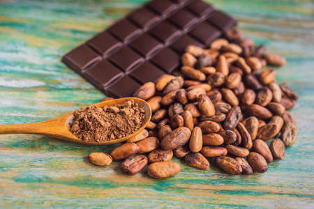 Chocolate and cocoa beans on color wooden background