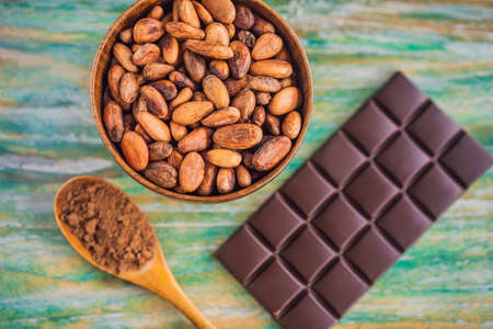 Chocolate and cocoa beans on color wooden background