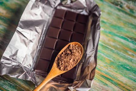 Chocolate and cocoa beans on color wooden background