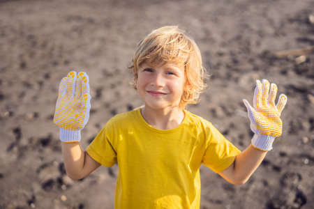 Young boy cleaning up the beach. Natural education of children
