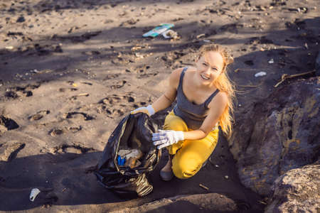 Young woman cleaning up the beach. Natural education of children
