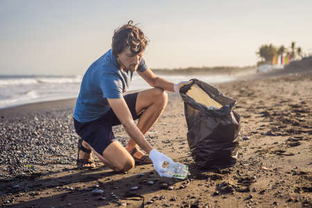 Young man cleaning up the beach. Natural education of childrenの写真素材