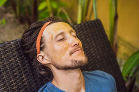Young handsome man makes a green cosmetic face mask. Skin Care for Men Concept