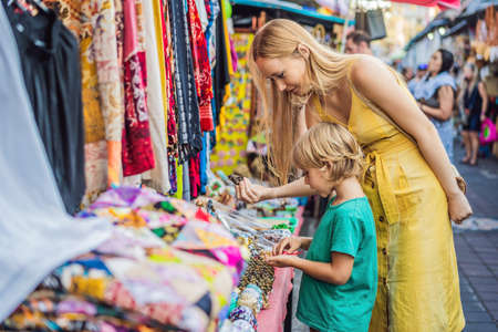 Mom and son travelers choose souvenirs in the market at Ubud in Bali, Indonesiaの写真素材