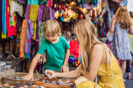 Mom and son travelers choose souvenirs in the market at Ubud in Bali, Indonesiaの写真素材